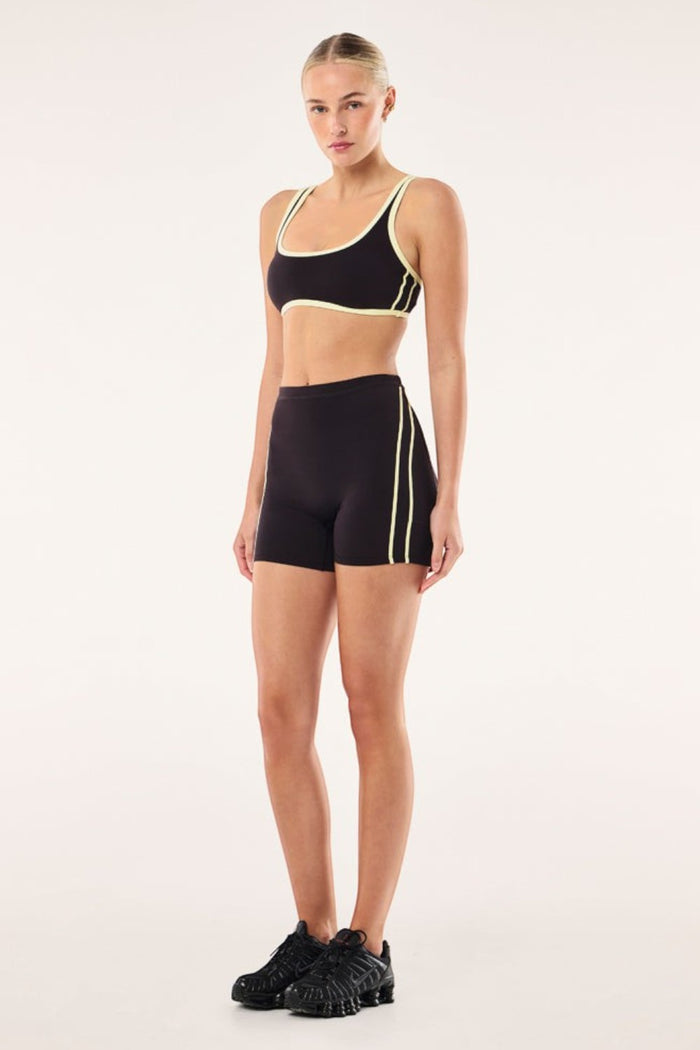 Model wearing ELSHAM BOUTIQUE Cypher bike shorts in black bean with soft yellow contrast side seams and high waistband