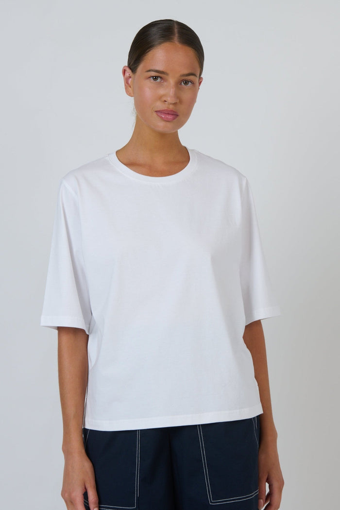 Model wearing an ELSHAM BOUTIQUE white cotton crew neck top with a relaxed boxy fit and elbow-length drop sleeves.