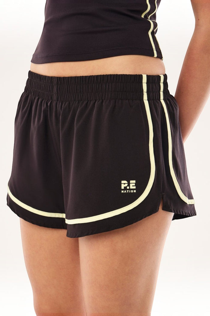 ELSHAM BOUTIQUE black athletic shorts with soft yellow piping trim and elastic waistband on a model