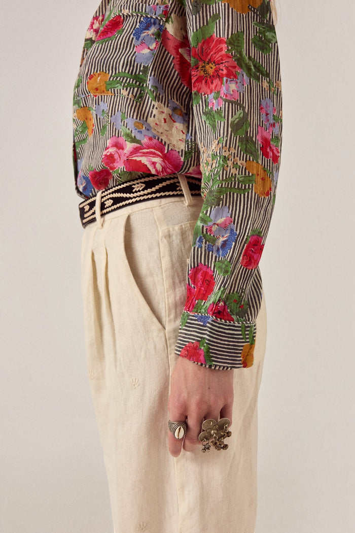 ELSHAM BOUTIQUE ivory cotton-linen Otto pants with front pleats and subtle embroidery, worn with a floral shirt.