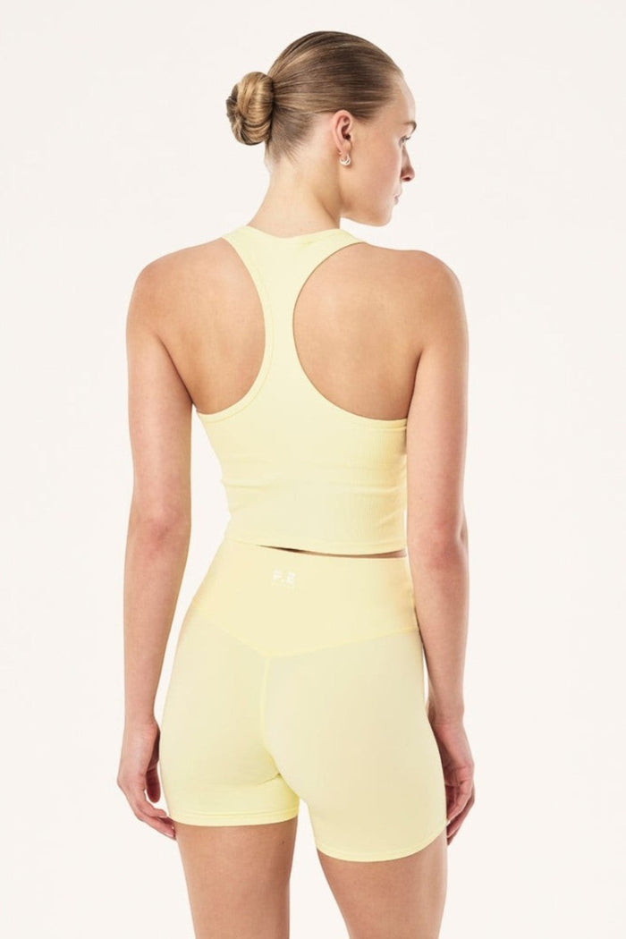 ELSHAM BOUTIQUE soft yellow ribbed racerback tank top with internal shelf bra worn by a model from the back view