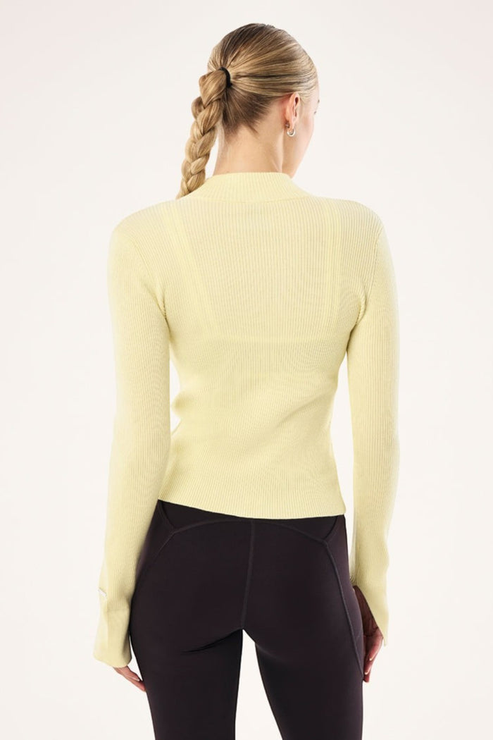 Back view of ELSHAM BOUTIQUE soft yellow rib knit zip jacket with high neck and long sleeves on a model
