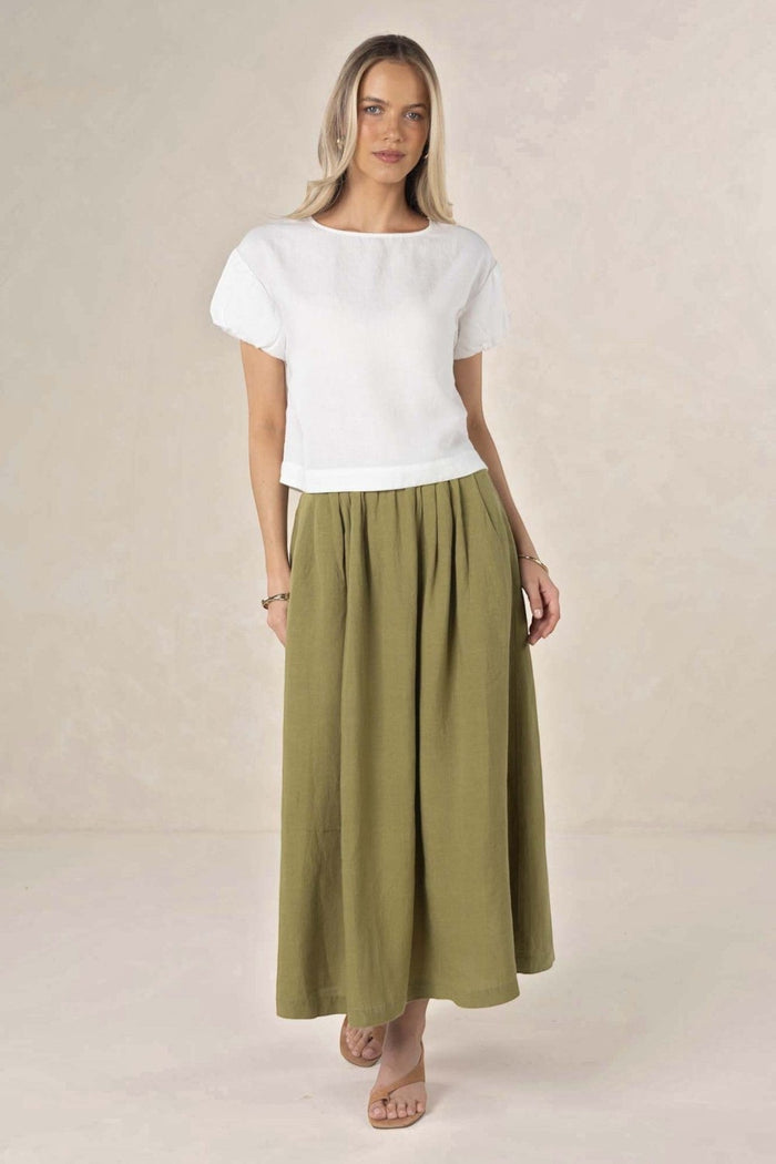 Model wearing an ELSHAM BOUTIQUE olive green linen-tencel midi skirt with an A-line silhouette and side pockets.