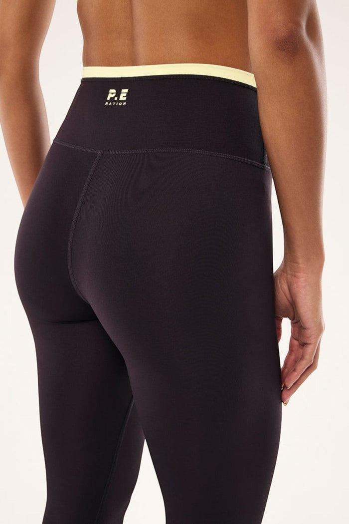 ELSHAM BOUTIQUE Vita full length leggings in black bean with a soft yellow high-rise waistband and P.E Nation logo.